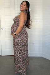 woman wearing a floral print maternity maxi dress and proudly showcasing her baby bump
