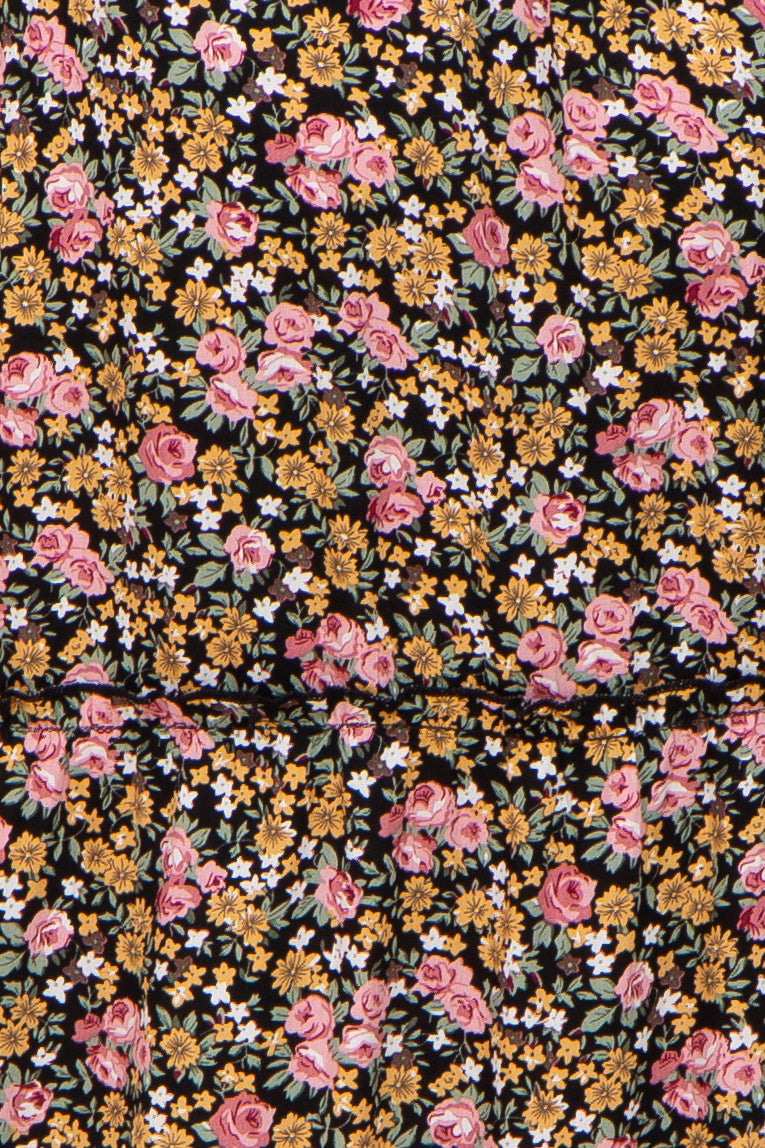 Close-up of black fabric with a vintage floral print featuring pink roses, yellow daisies, and white blossoms