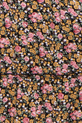 Close-up of black fabric with a vintage floral print featuring pink roses, yellow daisies, and white blossoms