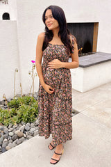 woman wearing a black floral maternity maxi dress and holding her baby bump