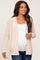 woman wearing a light pink open knit maternity cardigan and a white maternity top, showing her baby bump