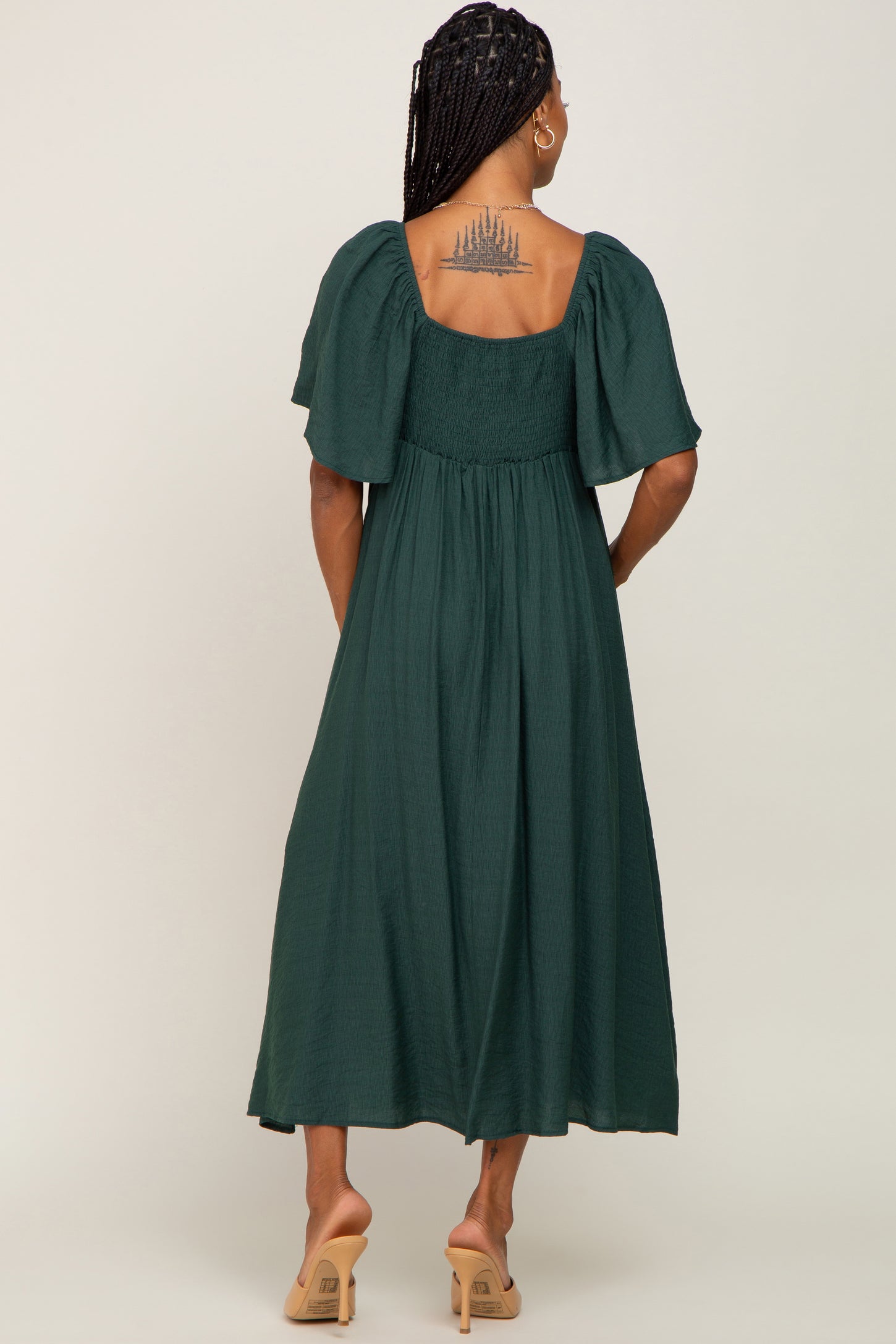 woman wearing a dark green textured midi dress with puff sleeves, showing a tattoo on her back