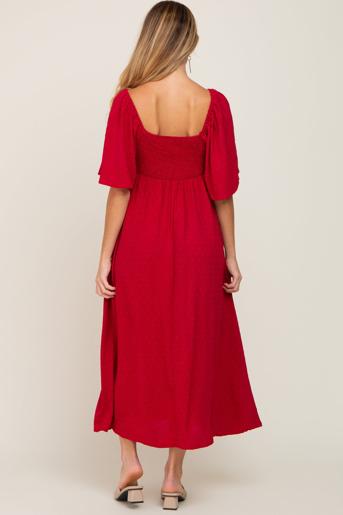 woman wearing a red maternity dress with a smocked bodice and short puff sleeves, showing a baby bump from the back