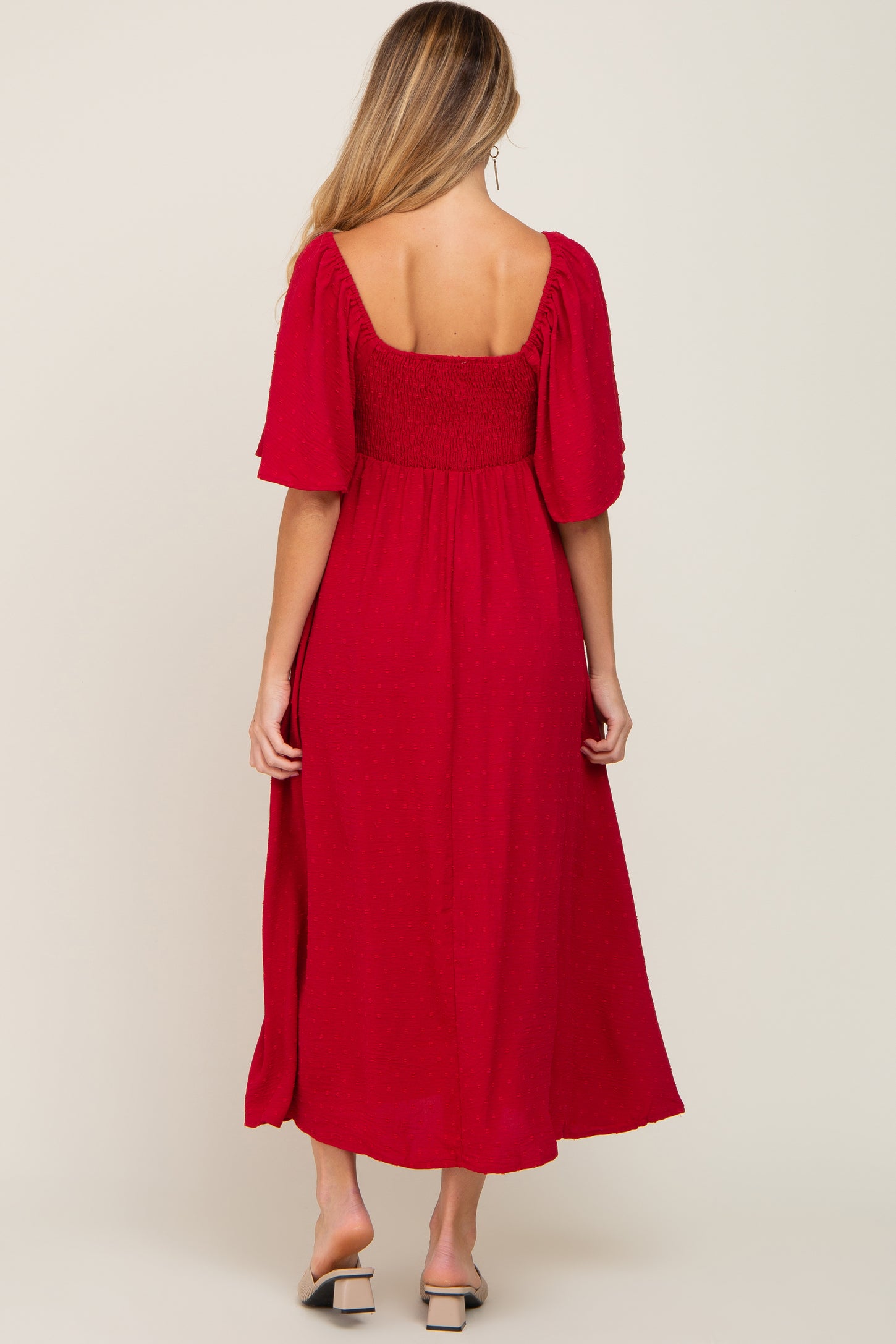 woman wearing a red maternity dress with a smocked bodice and short puff sleeves, showing a baby bump from the back