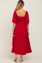 woman wearing a red maternity dress with a smocked bodice and short puff sleeves, showing a baby bump from the back