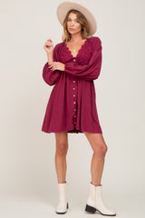 woman wearing a burgundy button-up dress with lace details and long sleeves, paired with a wide-brimmed hat and ankle boots