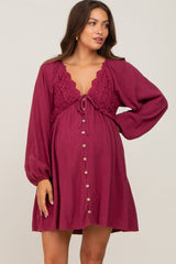 woman wearing a burgundy maternity dress with crochet detailing, long sleeves, and button closure, showing her baby bump