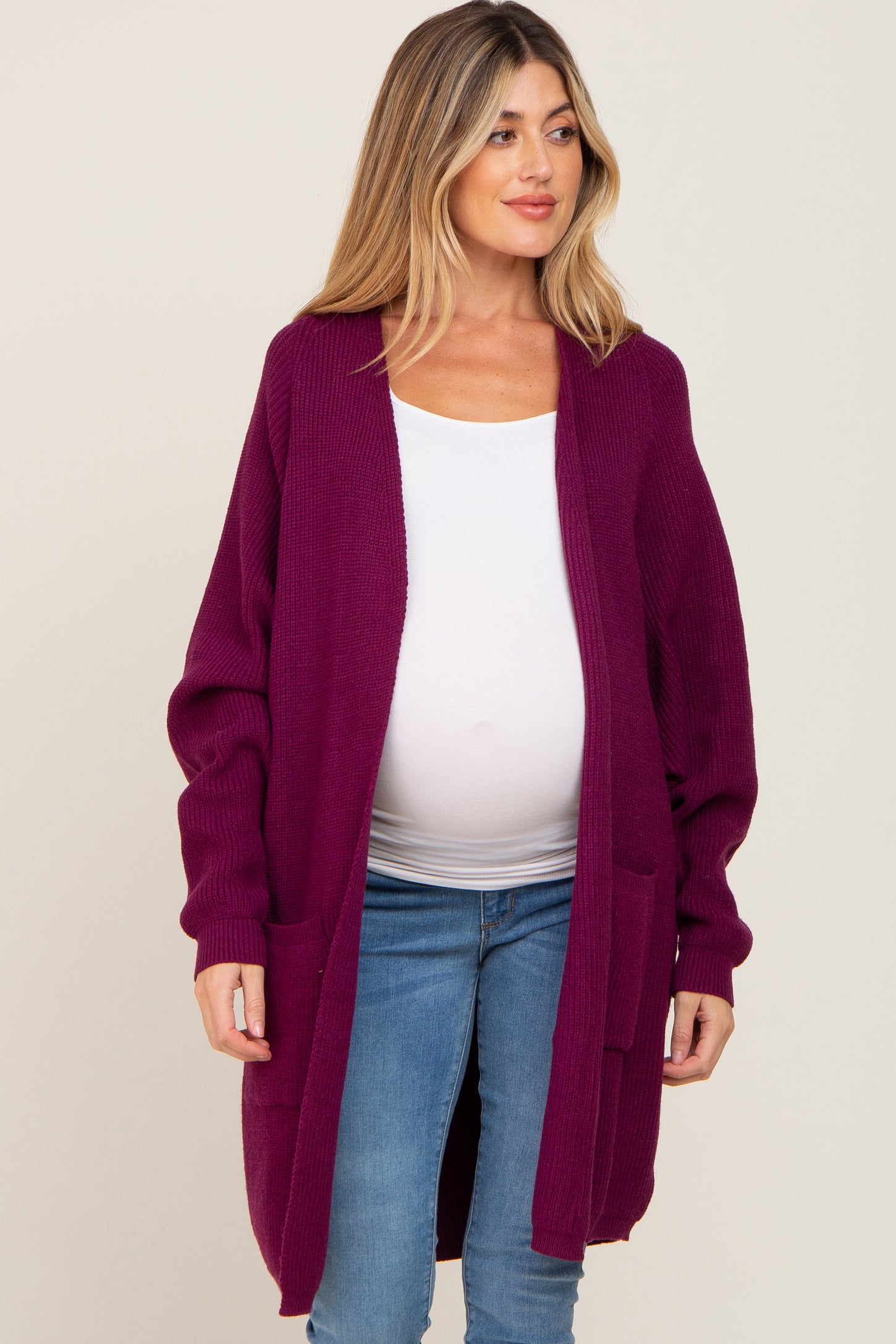 woman wearing a burgundy long sleeve maternity cardigan with pockets and a visible baby bump