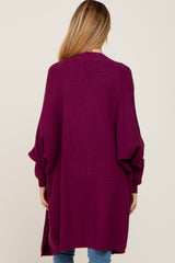 woman wearing a long, oversized plum maternity cardigan with balloon sleeves, seen from the back
