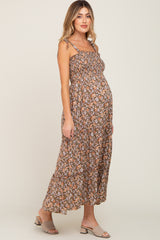 woman wearing a brown floral maternity maxi dress with tied straps and a visible baby bump