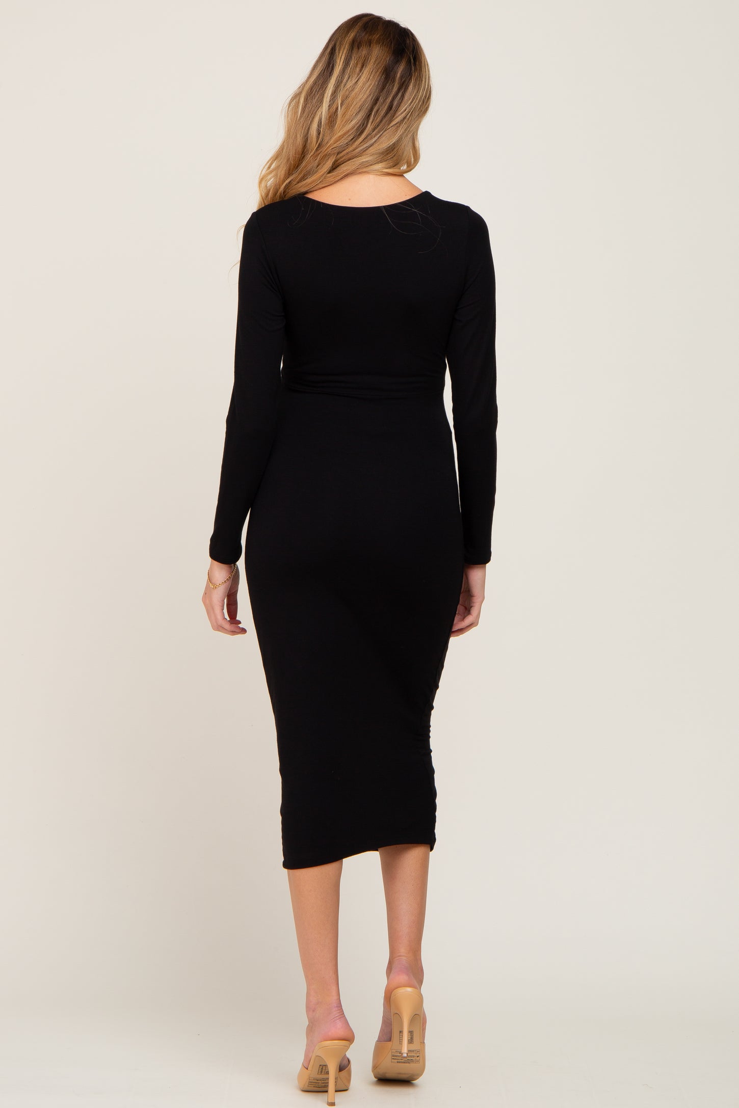 woman wearing a black long sleeve maternity dress, showing a fitted silhouette and midi length from the back
