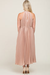 woman wearing a blush pleated maternity dress with a halter neck and a flowing silhouette from the back
