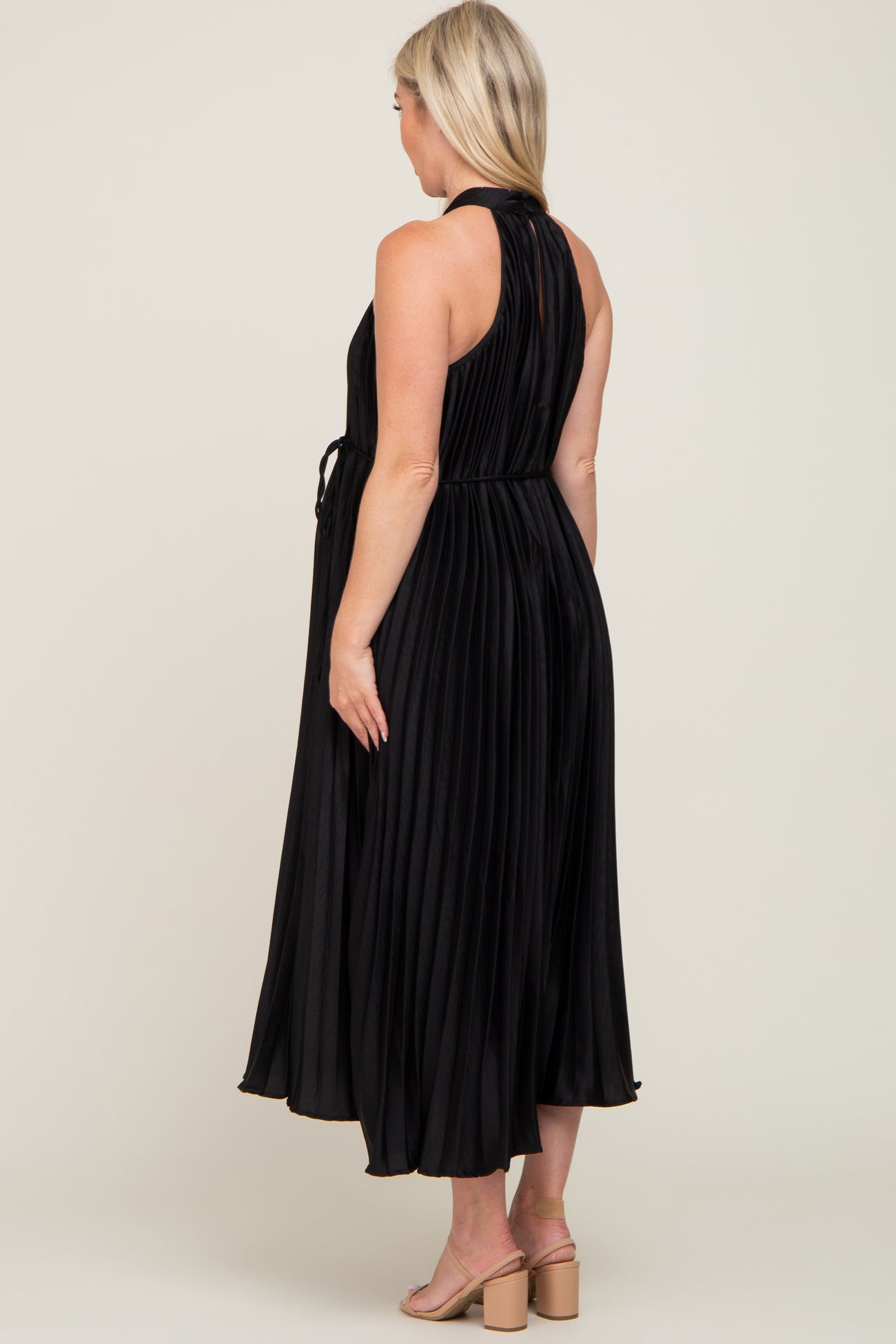 woman wearing a black pleated maternity dress with a tied waist, viewed from the back