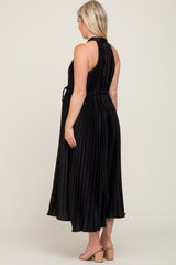 woman wearing a black pleated maternity dress with a tied waist, viewed from the back