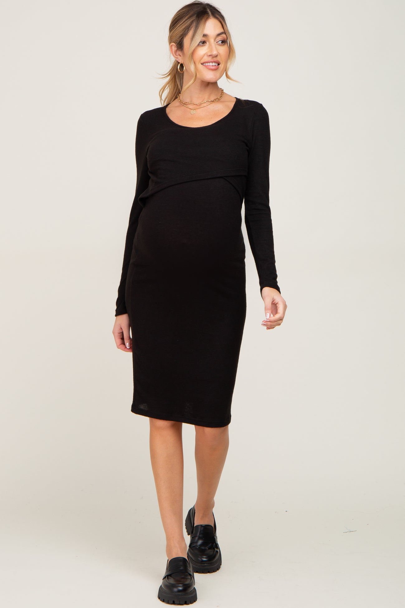 pregnant woman wearing a long sleeve black maternity midi dress with nursing access and black loafers