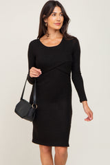 woman wearing a black long sleeve dress with a twist detail, holding a black handbag