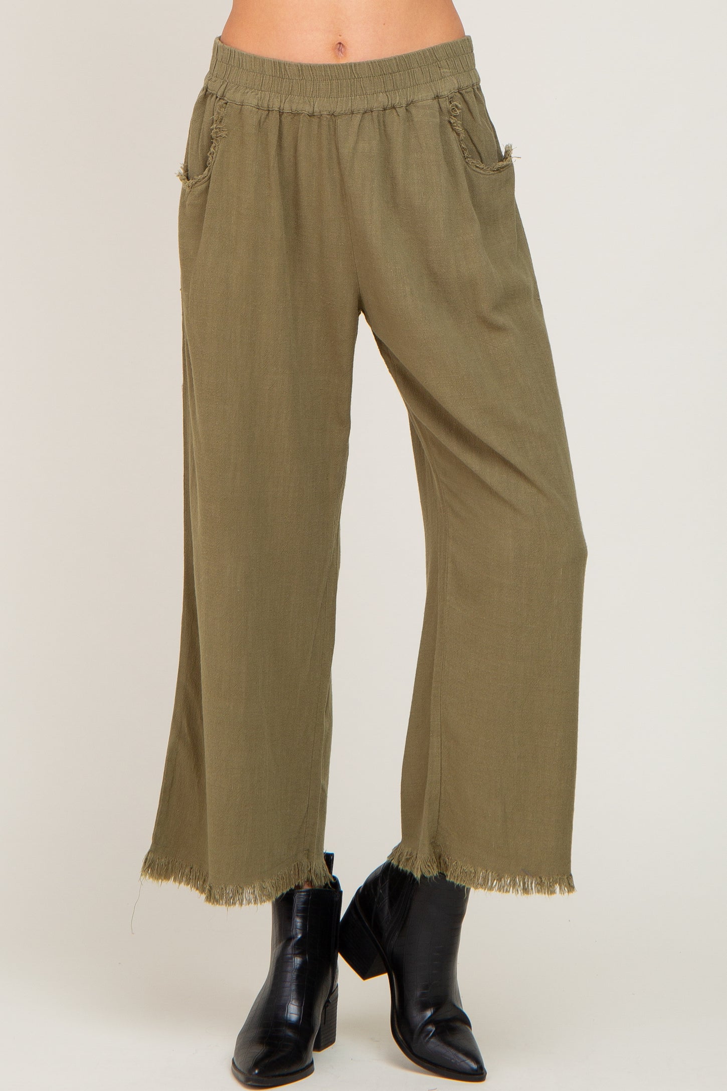 woman wearing olive green wide-leg pants with fringe hem and pockets, paired with black ankle boots