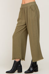 woman wearing olive green wide-leg pants with frayed hem and elastic waistband, paired with black ankle boots