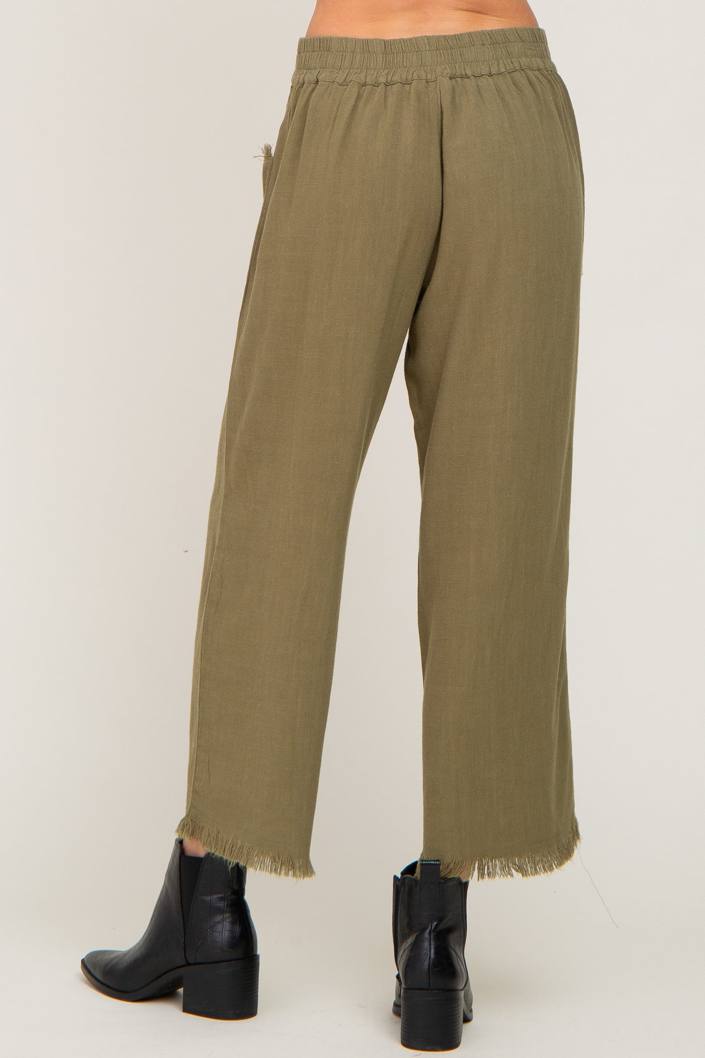 woman wearing olive green wide-leg pants with raw hem detail and an elastic waistband, view from the back