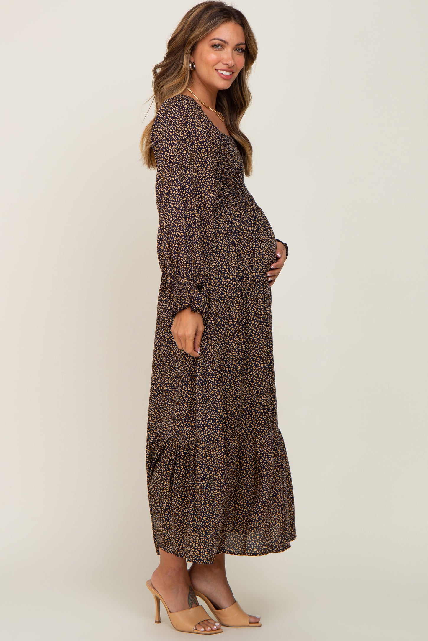 woman wearing a black and mustard floral maternity maxi dress, showing her baby bump with long sleeves and tiered skirt