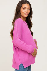 woman wearing a bright pink oversized maternity sweater and holding her baby bump