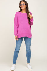 woman wearing a hot pink oversized maternity sweater and blue skinny jeans, posing with sunglasses and a baby bump visible