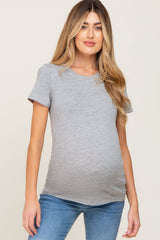 woman wearing a light gray short sleeve maternity top and showing her baby bump