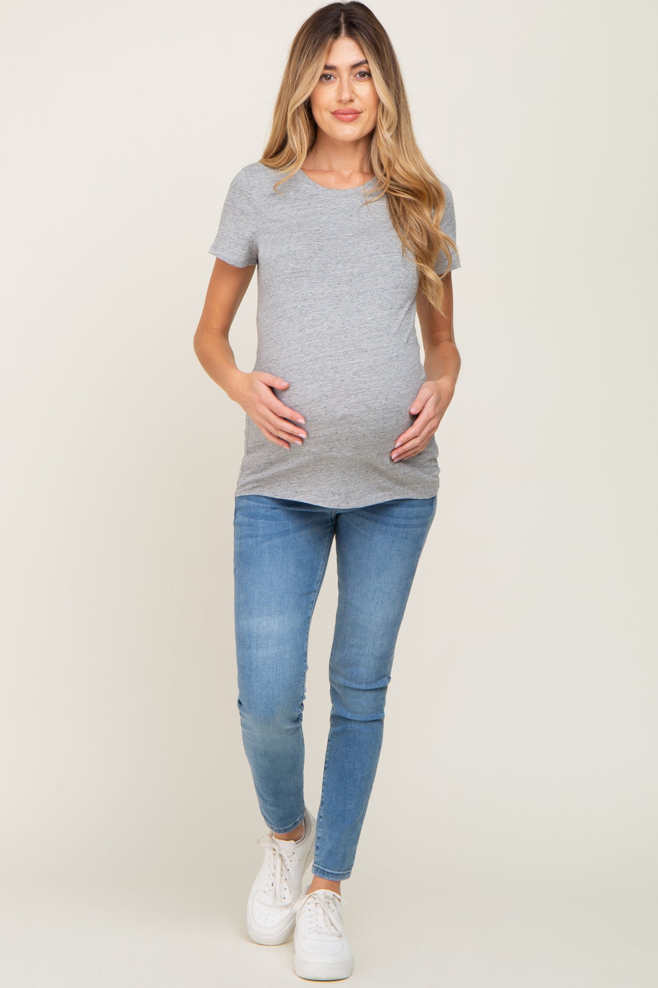 woman wearing a grey short sleeve maternity t-shirt and light blue skinny jeans, displaying her baby bump