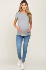 woman wearing a grey short sleeve maternity t-shirt and light blue skinny jeans, displaying her baby bump