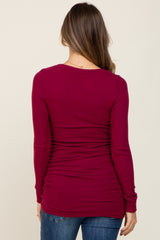woman wearing a dark red maternity long sleeve top with ruched sides, viewed from the back
