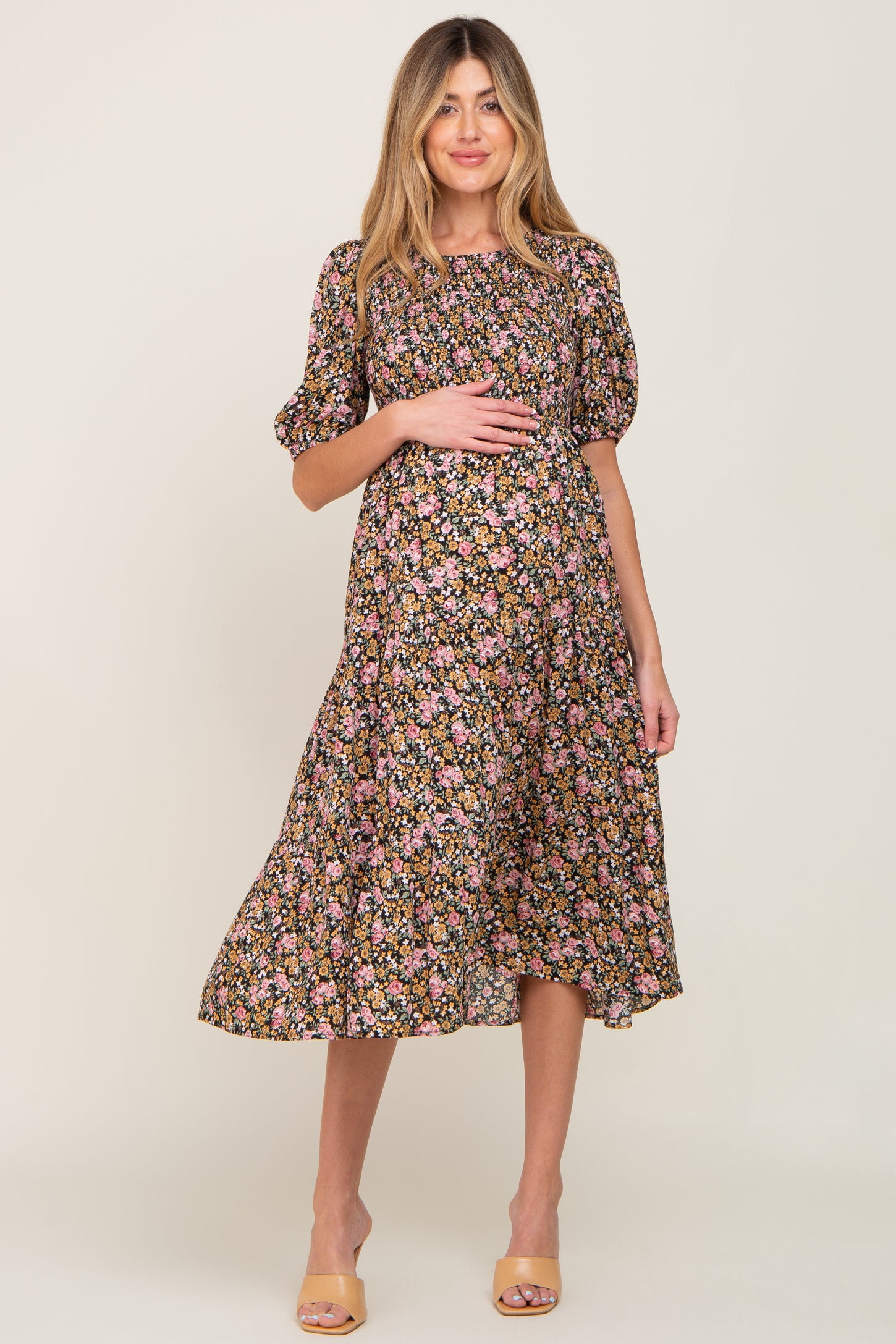 woman wearing a black floral maternity dress with short puff sleeves and a visible baby bump
