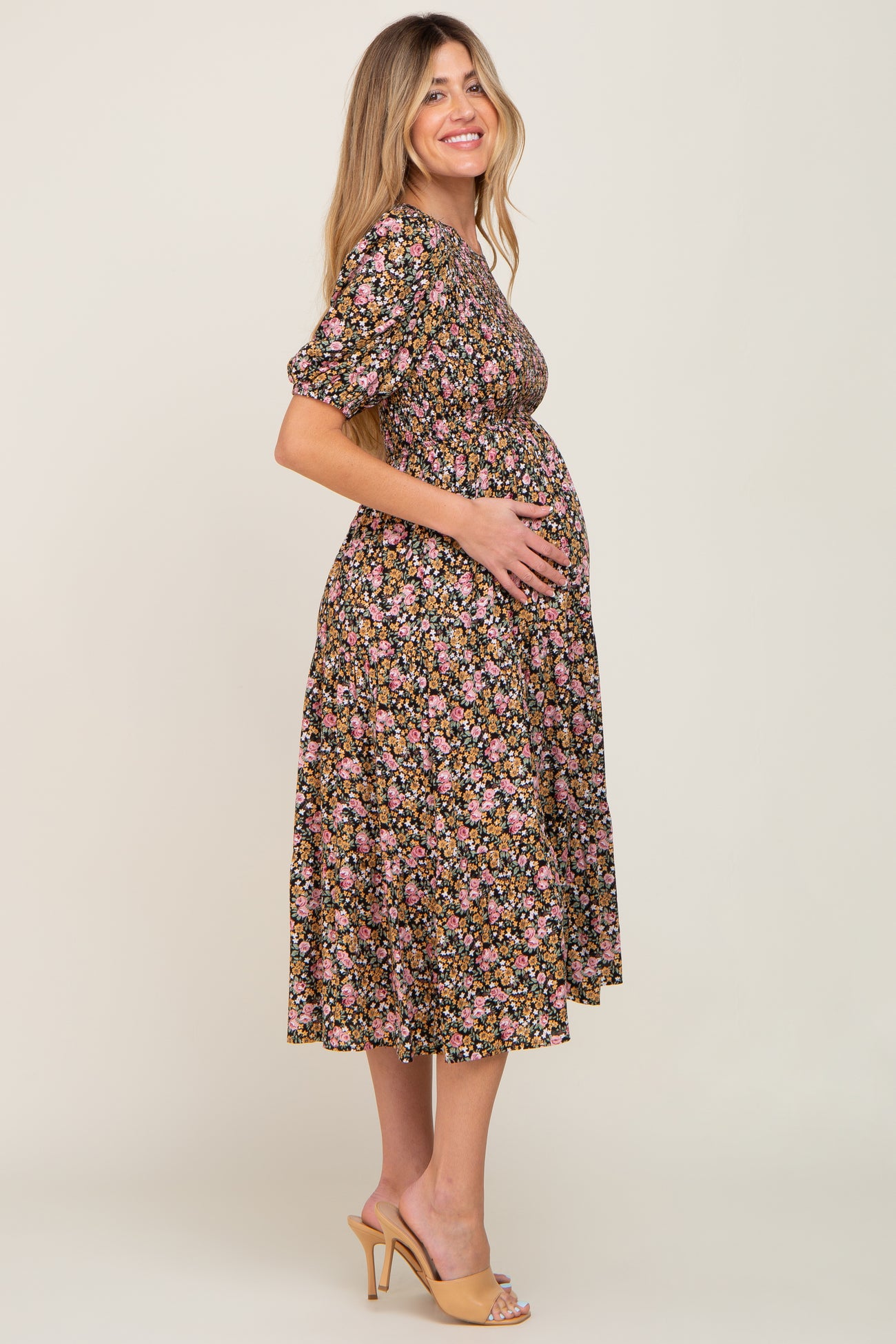 woman wearing a black floral maternity dress and holding her baby bump