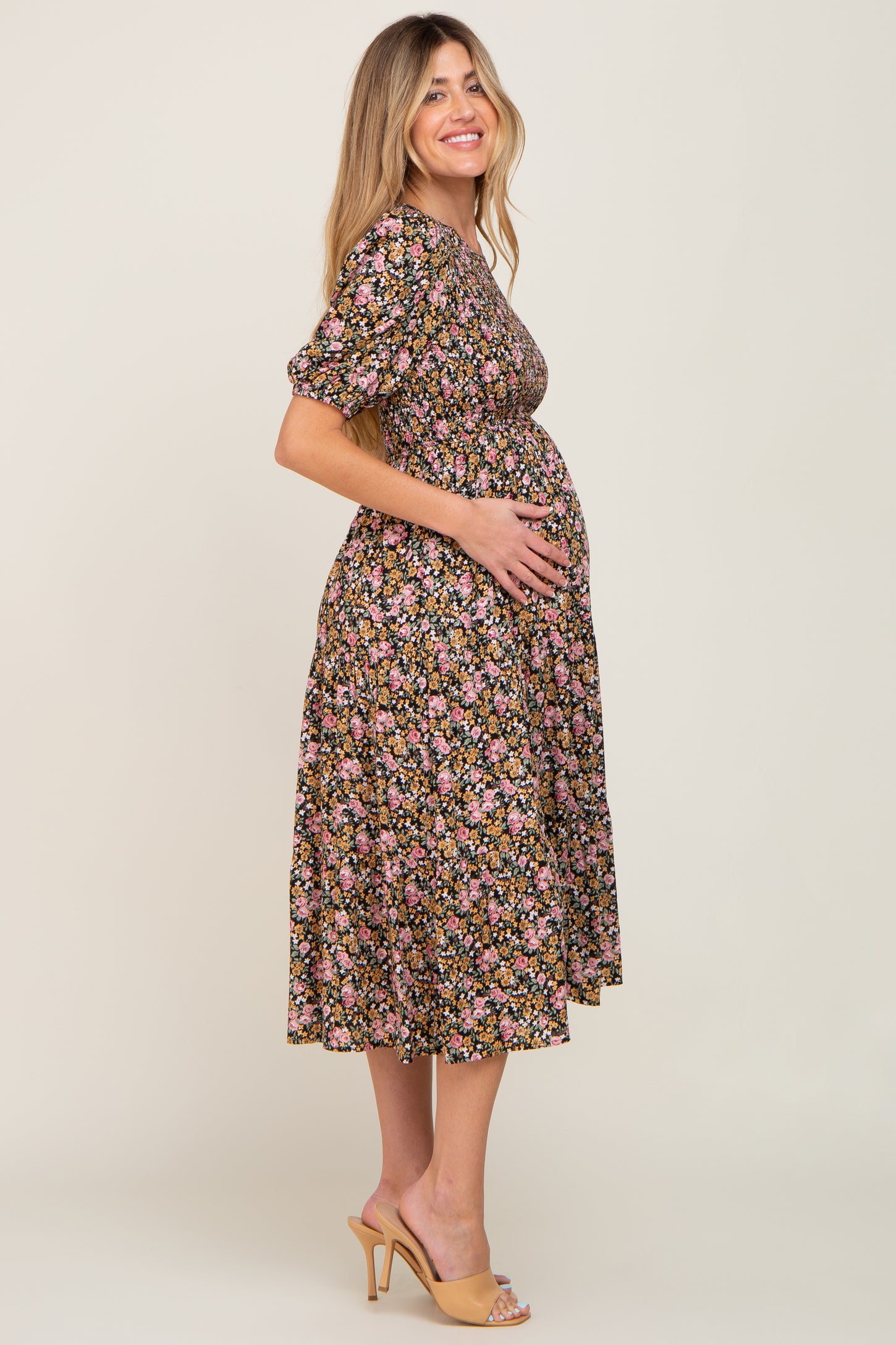 woman wearing a black floral maternity dress and holding her baby bump