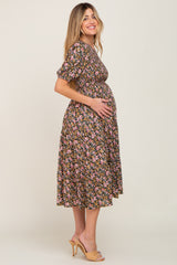 woman wearing a black floral maternity dress and holding her baby bump