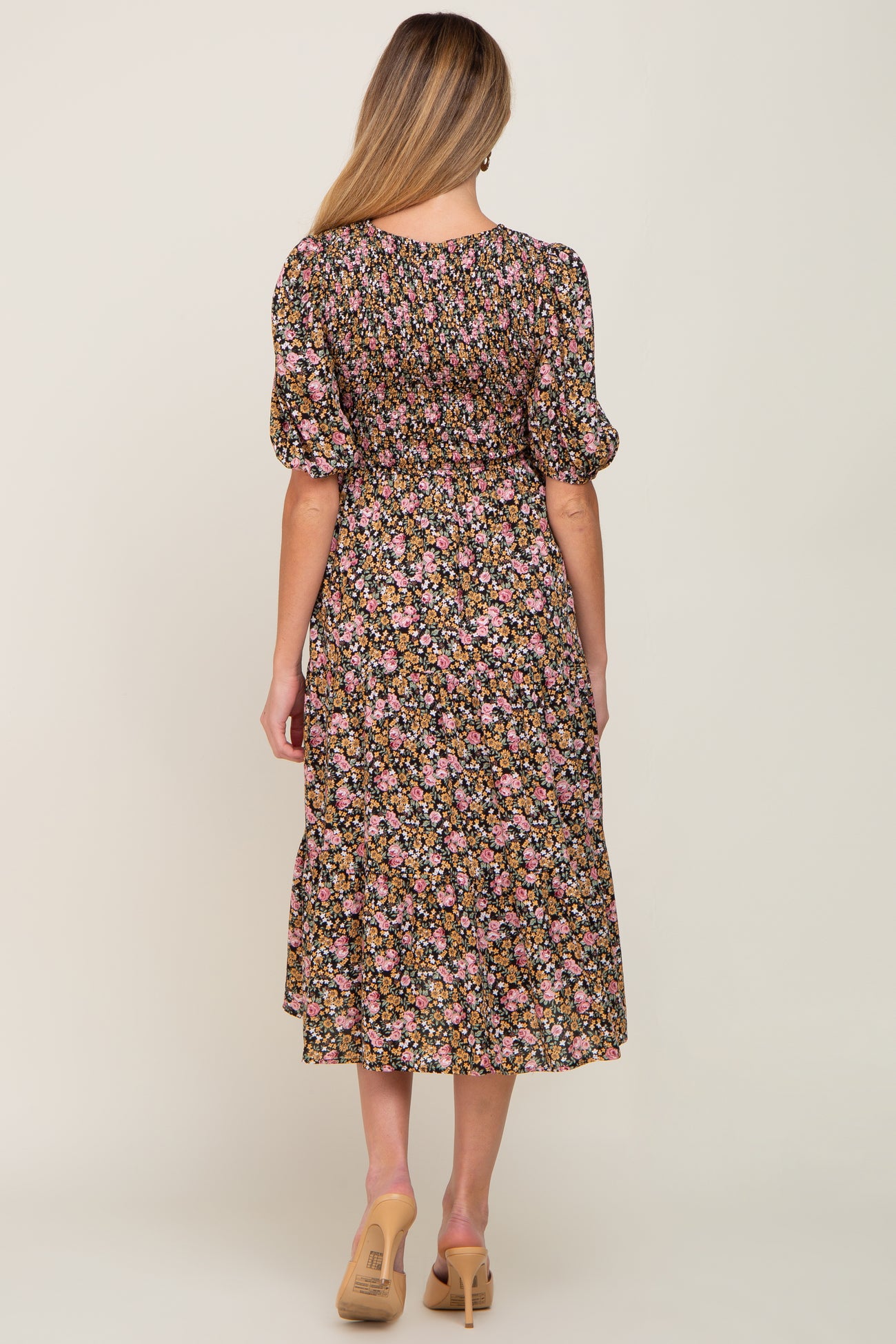 Back view of woman wearing a floral smocked midi dress with puff sleeves and tan heels