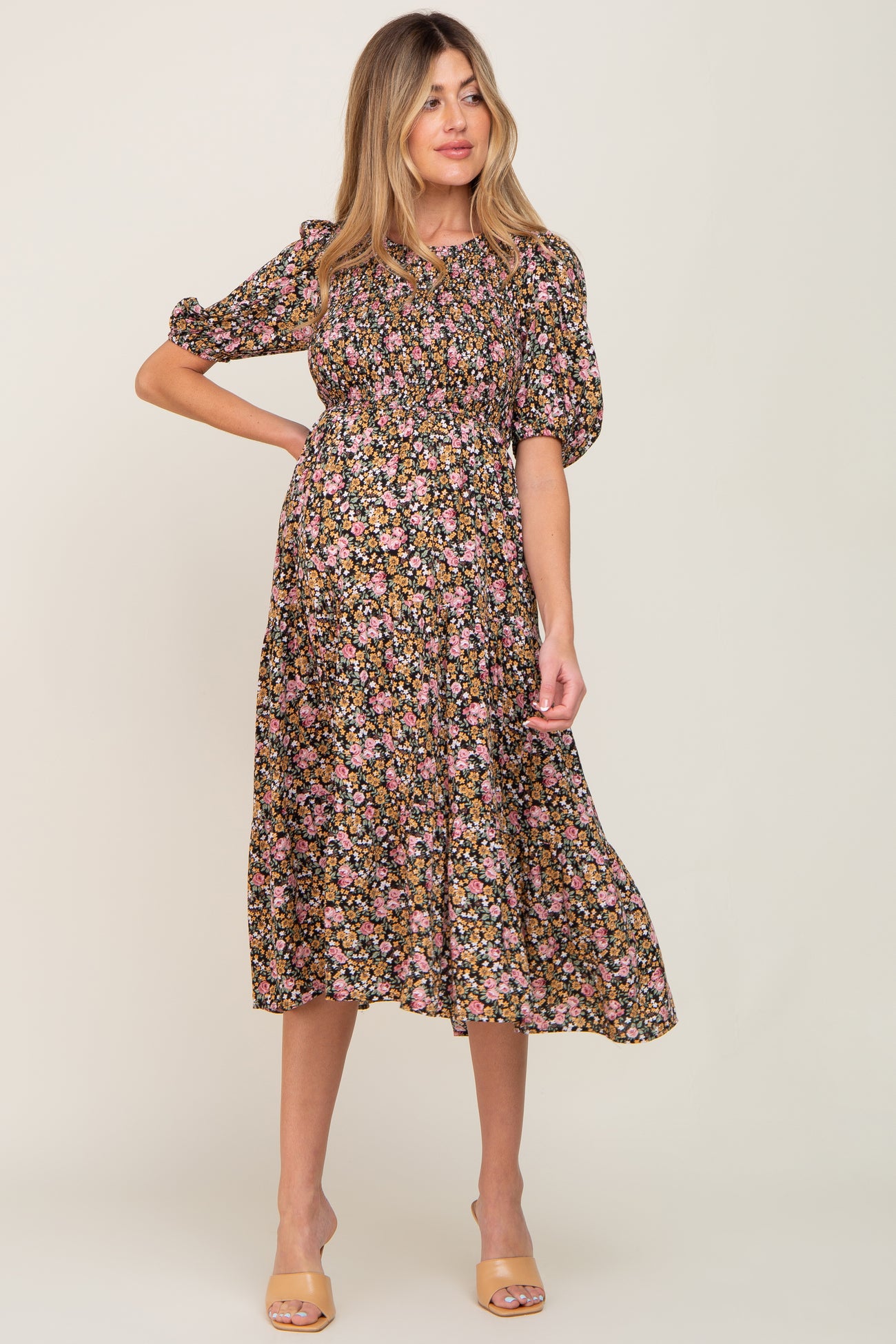 woman wearing a black floral maternity dress with puff sleeves and a cinched waist, showcasing her baby bump