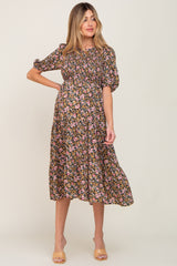 woman wearing a black floral maternity dress with puff sleeves and a cinched waist, showcasing her baby bump