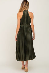 Back view of a woman wearing an olive green pleated halter midi dress with tan high heels