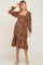 woman wearing a brown floral maternity dress with a square neckline and long sleeves, featuring a ruffled hem and a visible baby bump