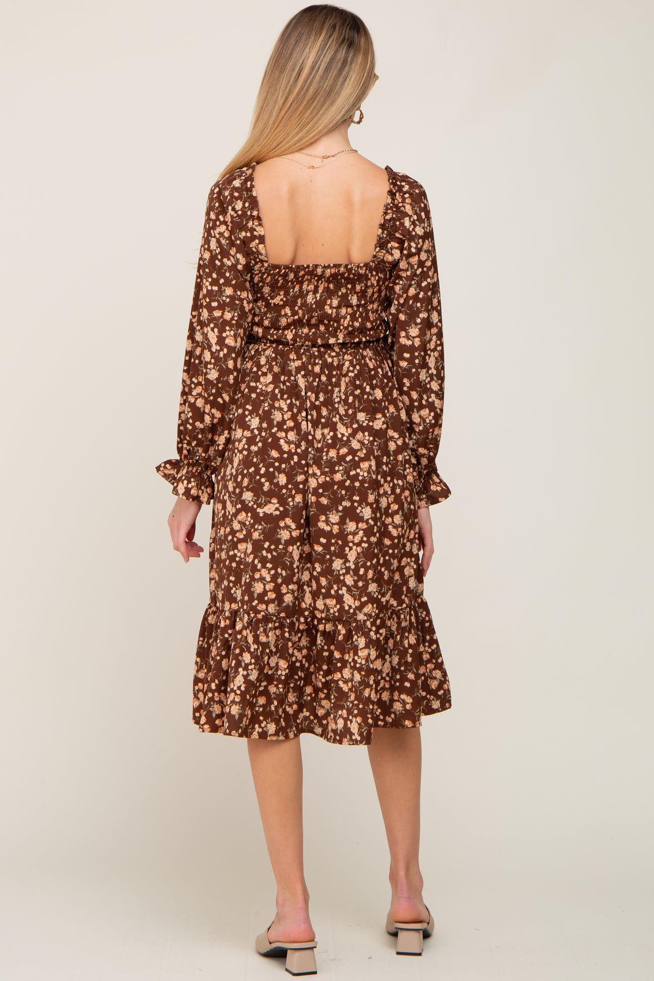 woman wearing a brown floral long sleeve maternity dress with a fitted bodice and ruffled hem