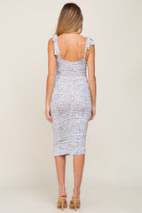 woman wearing a light blue floral print maternity dress with ruched details and tie straps