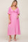 woman wearing a pink maternity dress with a tie front and short flutter sleeves, holding her baby bump