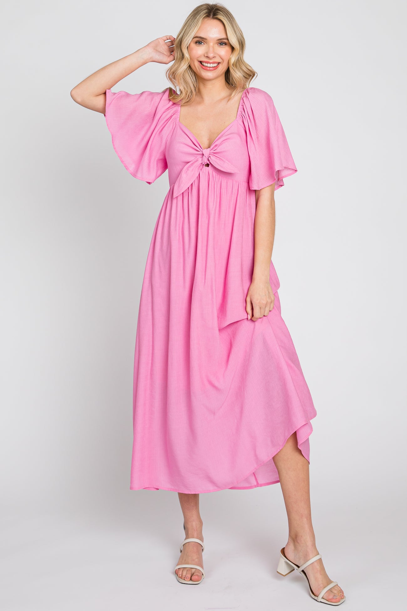 woman wearing a pink flutter sleeve maxi dress with a front knot detail