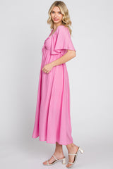 woman wearing a pink short sleeve maxi dress with a tie front and flowy silhouette