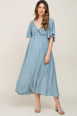 woman wearing a light blue maternity maxi dress with a tie-front and flutter sleeves, showcasing a baby bump