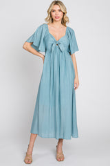 woman wearing a light blue midi dress with flutter sleeves and a tie-front bodice