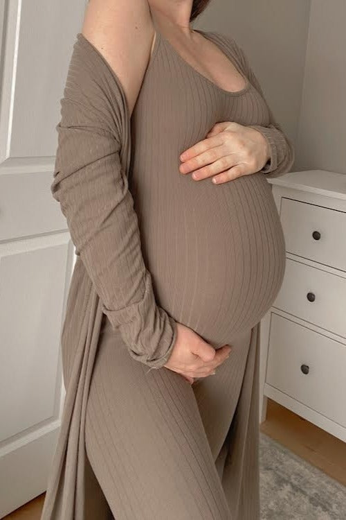 pregnant woman in ribbed tan maternity loungewear set holding her baby bump