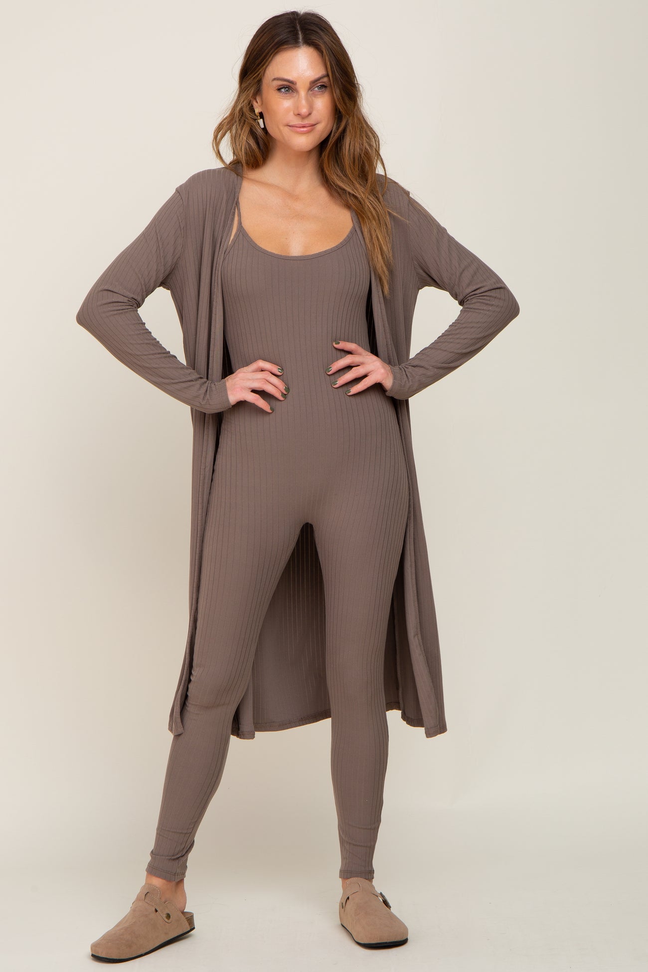 Woman wearing a mocha brown ribbed jumpsuit and matching long cardigan with tan clogs