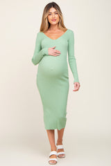 woman wearing a green ribbed long sleeve maternity dress and holding her baby bump