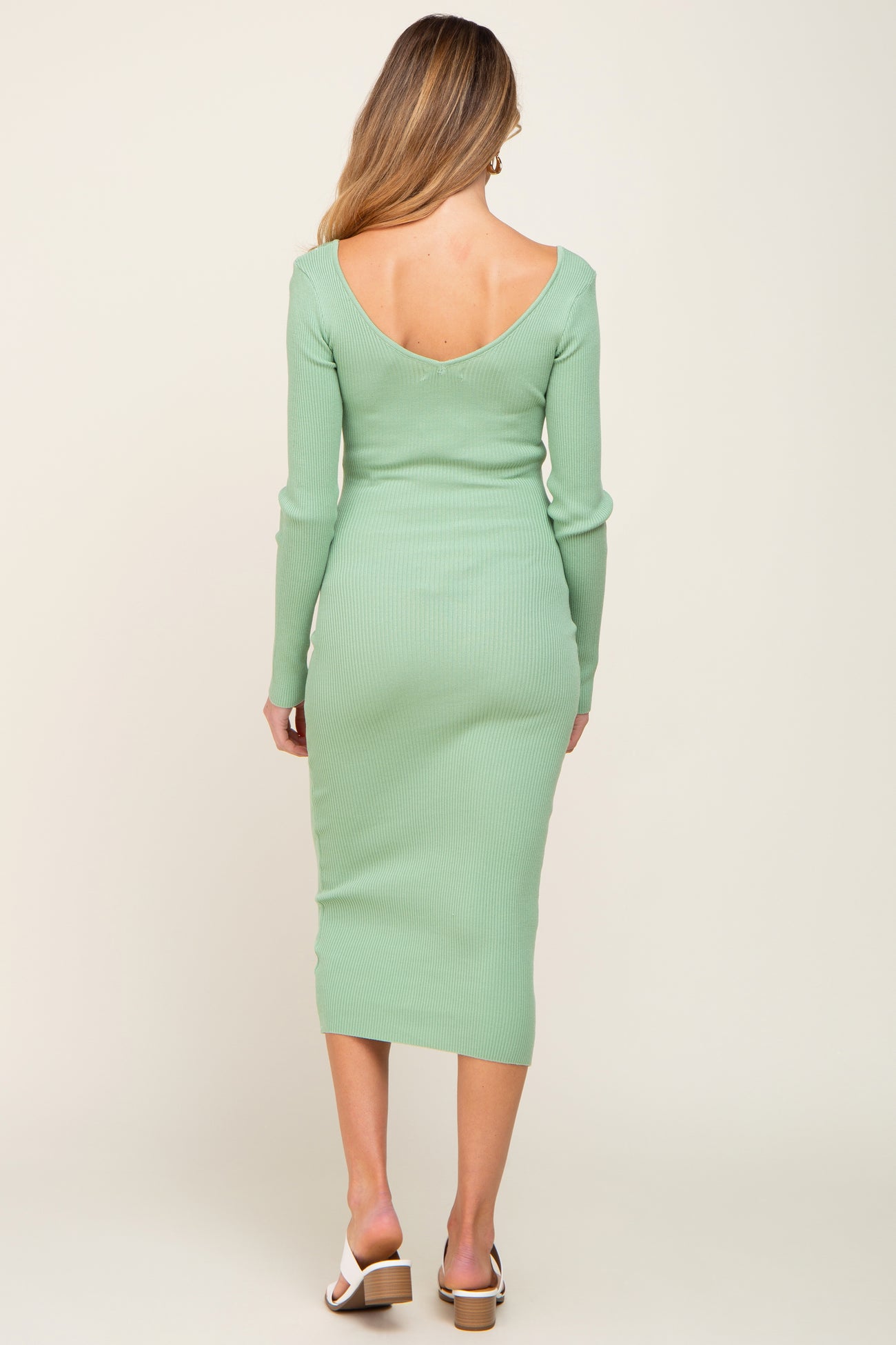 woman wearing a mint green long sleeve ribbed maternity dress with a deep back neckline